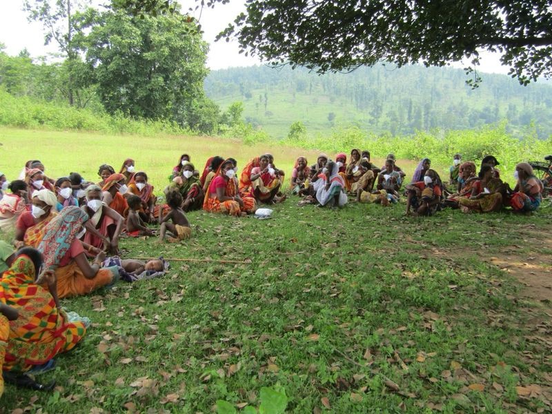 Women seated in a Gram Sabha meeting outdoors
